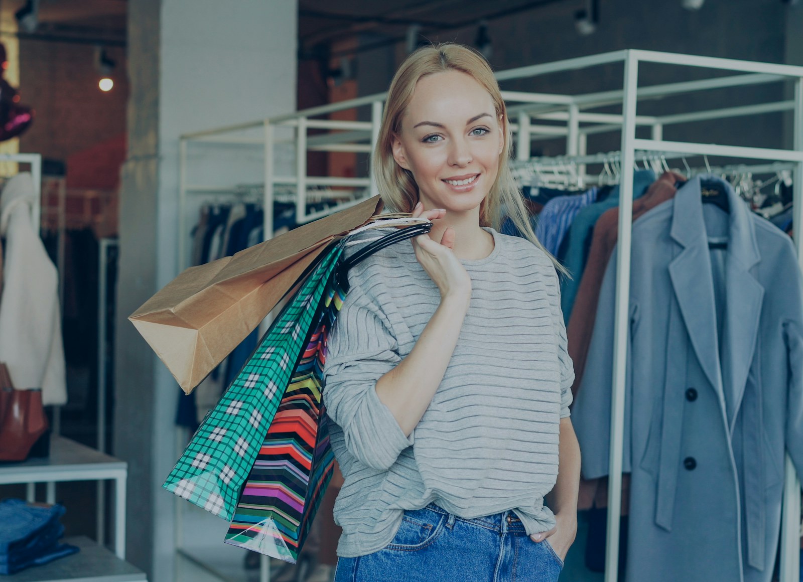 A smiling shopper carrying colorful shopping bags in a bright clothing store